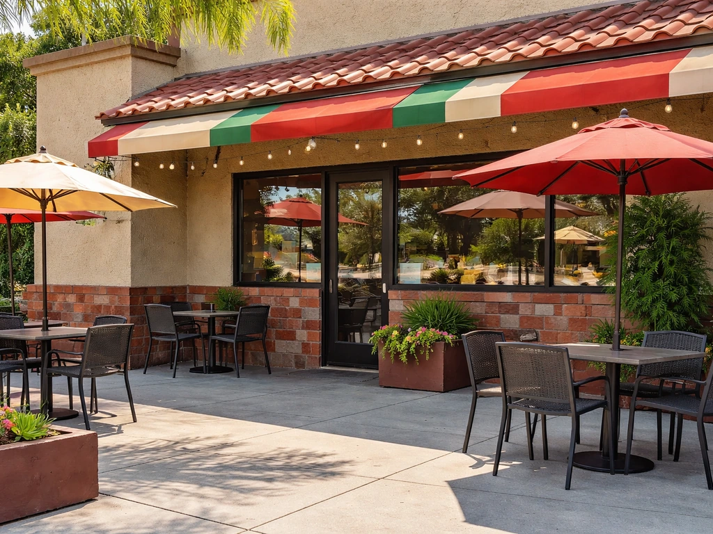 Quiet outdoor patio seating in front of a casual taco restaurant storefront in natural daylight.